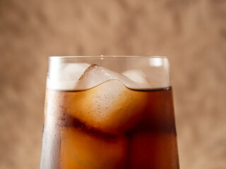 Cola with ice in a glass. Carbonated refreshing drink with ice. Cola bubbles.