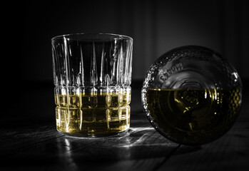 whisky in a glass with a bottle in black and white with color editing