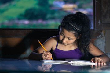 latina girl, brunette studying. little girl concentrating on her homework, leaning on a glass table. - obrazy, fototapety, plakaty