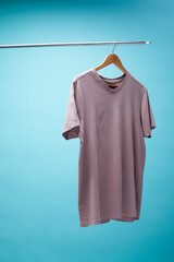 Purple t-shirt  hanging on a hanger isolated on blue background.