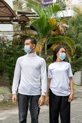 A couple wearing blank white shirt and a face mask doing a pose at the outdoor