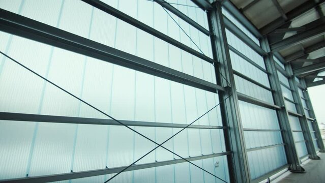 Hollow polycarbonate panels on metal hangar frame. Semitransparent walls of building materials warehouse. Modern strong reinforcing thermoplastic closeup