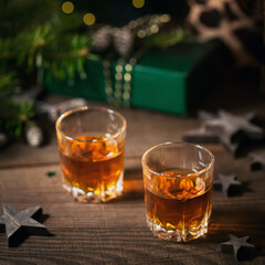 Whiskey, brandy or liquor shot and Christmas decorations on wooden background. Winter holidays concept.