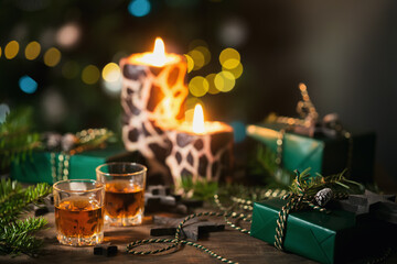 Two shot glasses of whiskey or bourbon with Holiday decoration on wooden background. New Year, Christmas and winter holidays whiskey mood concept