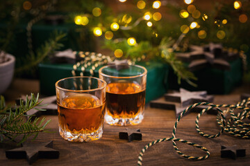 Whiskey, brandy or liquor shot and Christmas decorations on wooden background. Winter holidays concept.