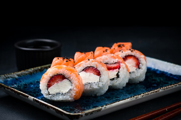 Sushi rolls with raw salmon fish, cream cheese, strawberry and sauce.