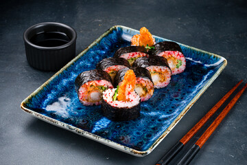 Sushi rolls with shrimp tempura, cream cheese, lettuce, cucumber, red flying fish caviar and soy sauce.