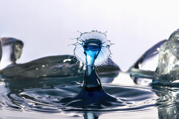 Macro background of the collision of drops over the surface of the water against the background of pieces of ice.