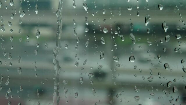 Raindrops on the window. Its raining outside. Close-up shot. View from the window to the road with passing cars. type 3