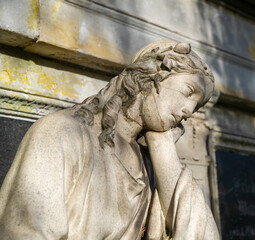Die Frau in tiefer Trauer lehnt am Grabstein auf einem Friedhof in Osnabrück