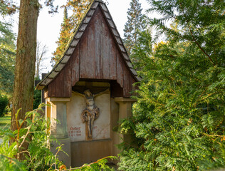 Fototapeta na wymiar Überdachter Grabstein mit der Jesusfigur am Kreuz auf einem Friedhof in Osnabrück