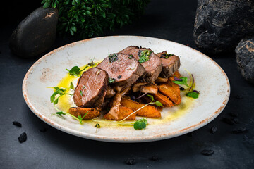 Beef medallions with mushroom sauce and fried potato wedges in a plate.
