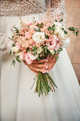 The bride holds a wedding bouquet in her hands. Festive theme.