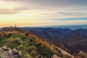 Naklejka na ściany i meble View from a height of 1000 m on the mountain peaks of the Black Sea coast of the Caucasus. Stunning view of the mountain landscape from a height. View at dawn from the top of Mount Peus.