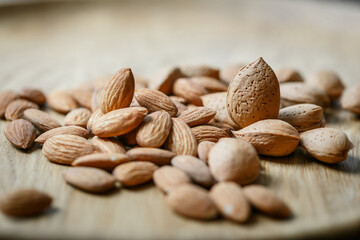 Peeled raw almonds and almonds in a shell on a  wooden background.