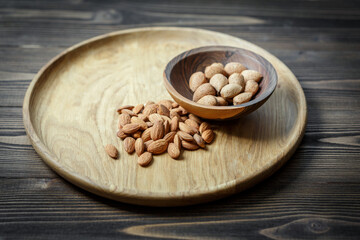 Fototapeta na wymiar Peeled raw almonds on a wooden plate and almonds in a shell in a wooden bowl on a wooden background.