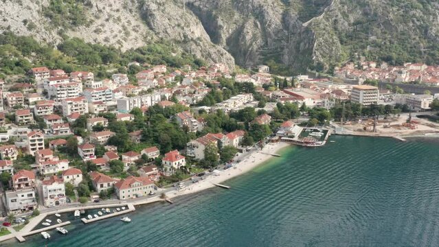 Kotor Montenegro waterfront - Roofs on houses and buildings along the coastline, in residential neighborhood of Dobrota, between rocky hills and Mediterranean sea bay. Aerial drone view.