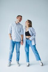 Relationship concept - photo of a happy couple in white shirts and jeans on a white background. Happy young couple