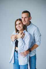 Photo of happy couple wearing white shirts, blue jeans, isolated white background. A man and a woman are hugging on a white background