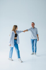 Photo of happy couple wearing white shirts, blue jeans, isolated white background. A man and a woman are hugging on a white background