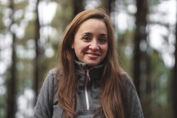 girl with brown hair in the middle of the forest being cold