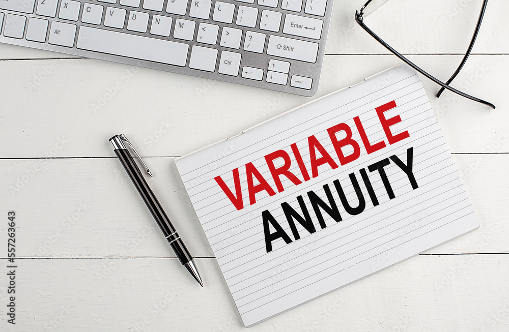 Poster variable annuity text on notebook with keyboard , pen glasses on white wooden background