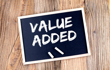 VALUE ADDED text on a chalkboard on the wooden background