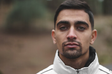portrait of boy with black hair and light eyes in the middle of the forest