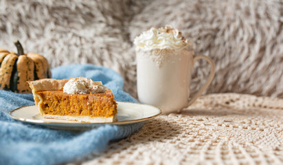 Pumpkin pie topped with whipped cream with coffee or chocolate and pumpkin in backround, rustic set with blue accents