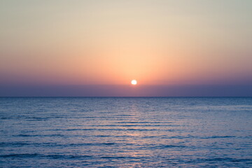 Beautiful sunrise at sea. Dawn on the Red Sea. The sun is reflected in the sea. Palm trees and palm leaves against the background of the rising sun. Tropical sunrise