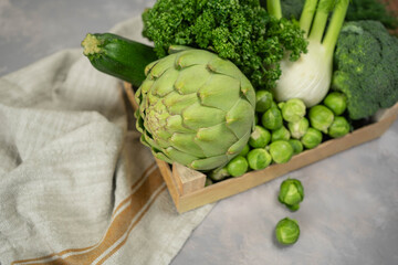 wooden box of green vegetables on gray cocrete background.