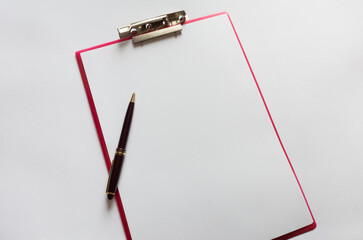 Doctor's working table with pen, blank medical record chart or test results on clipboard.
