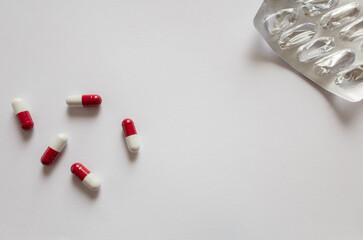 Pills red-white capsules. Blister packaging on a white background with a copy space.