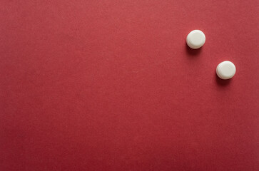 Small round white pills, lots of little tablets on red background close up. Simple group of little pills, medicine