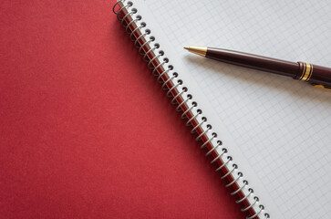 Doctor's working table with pen, blank medical record chart or test results on clipboard on a red background.