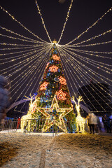 Photo of a festive Christmas tree on the square with a garland