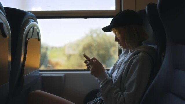 Teenage girl with smartphone travelling inside the train.