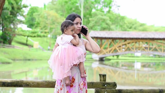 mother holding her baby while receiving a phone call. latina woman very worried while receiving a phone call.
