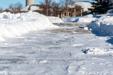 Selective focus ground level view of snow blown sidewalk section with path continuing. 