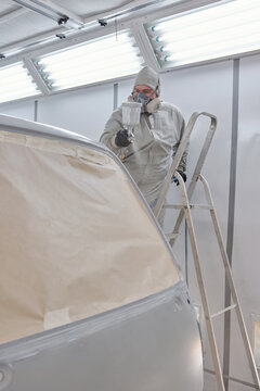 Vertical shot of unrecognizable man wearing work clothes and respirator painting truck