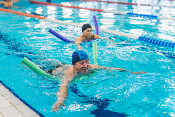 Senior couple in the swimming pool indoor. High quality photo