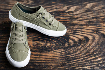 pair of fashionable sports shoes with a white sole on a dark wooden background.Space for text.
