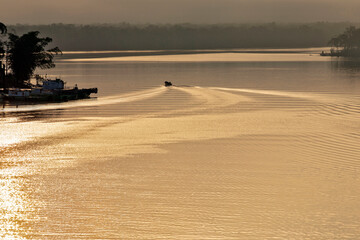 Boat creating waves in the golden waters of the sea. Guaruja, Sao Paulo state, Brazil