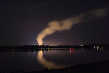Night view of  a pressurized water nuclear power plant located with steam arising from large cooling tower.
