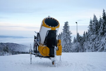 Yellow artificial snow cannon on Wasserkuppe ski resort in Rhoen Hesse Germany, on snowy mountain...