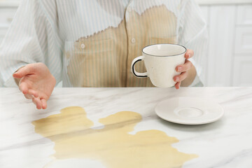 Woman with spilled coffee over her shirt at marble table indoors, closeup