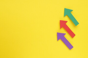 Paper arrows on yellow background, flat lay. Space for text