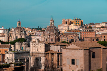 Fototapeta na wymiar The beautiful orange and blue skyline of the historical city of Italian Rome shows European urban architecture - basilicas, monuments, towers, buildings, and baroque temples noticeable by its cupolas.
