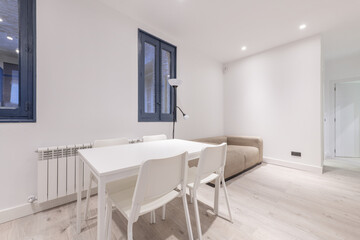 Fototapeta na wymiar Dining area of a vacation rental home with a white rectangular table with matching chairs and a fabric armchair