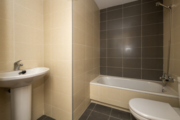 Small bathroom with white porcelain sanitary ware, wooden door and window made of a white aluminum sheet